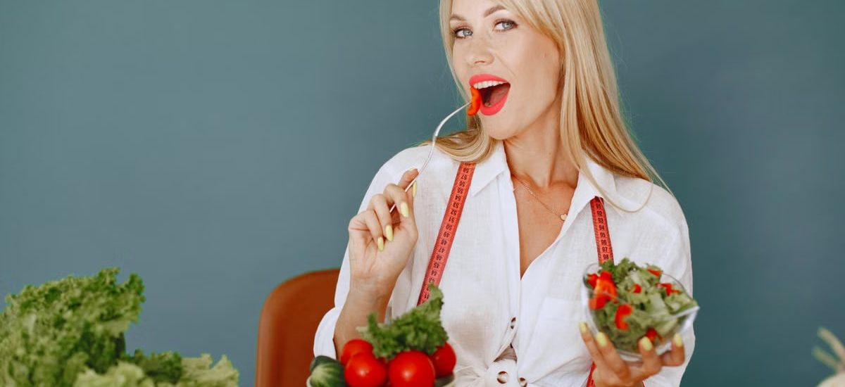 Woman enjoying a fresh salad with tomatoes and greens, promoting healthy eating.